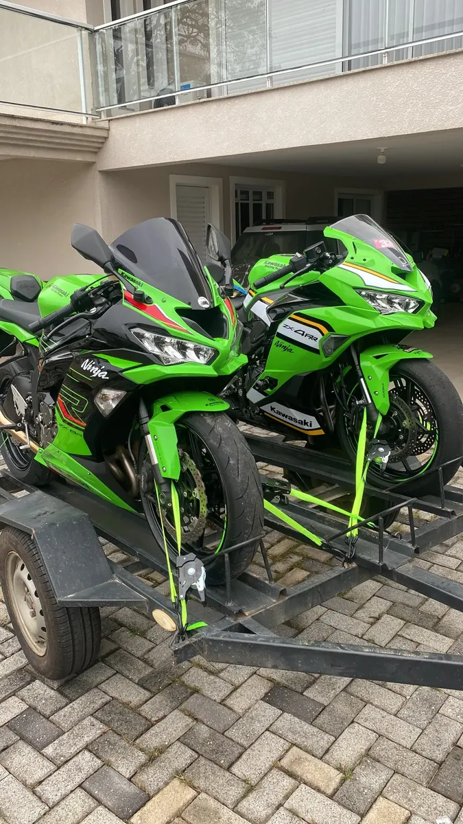 Duas motos esportivas presas em um reboque com cintas verdes